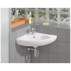 a white sink in a bathroom next to a window with glass blocks on the wall