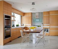 a modern kitchen with wooden cabinets and stainless steel appliances, including an island table surrounded by four chairs