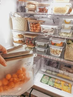 a refrigerator filled with lots of food and plastic containers on the shelves, including oranges