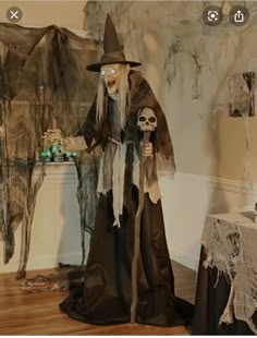 a man dressed as a witch standing next to a table