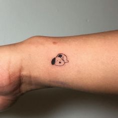 a person's arm with a small black and white dog head tattoo on it