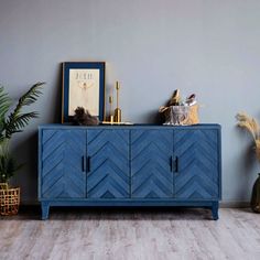 a blue sideboard sitting on top of a wooden floor next to a potted plant