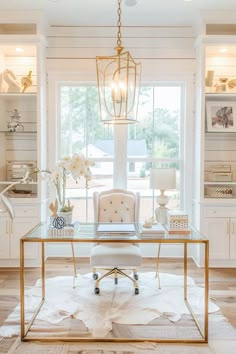 a white and gold desk in the middle of a living room with lots of windows