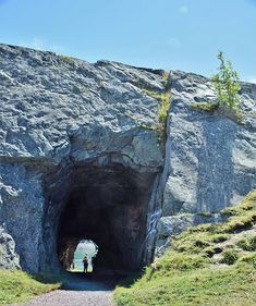 two people are standing at the end of a tunnel that is on top of a hill