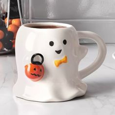 a coffee mug with a face painted on it and a halloween pumpkin in the middle