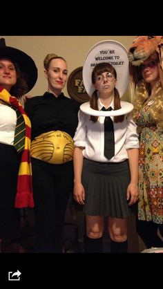 four women dressed up in costumes and hats posing for the camera with one woman holding a plate on her head