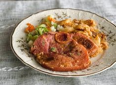 a white plate topped with meat and veggies on top of a blue table cloth