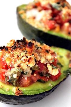 an avocado stuffed with tomatoes, cheese and other toppings is shown on a white surface