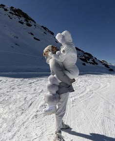 a person on skis holding onto another person in the snow with mountains in the background