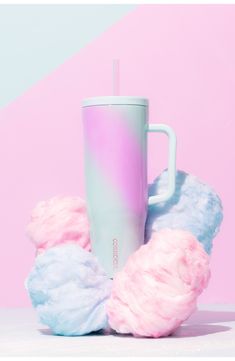 a pink and blue cup sitting on top of cotton balls next to a coffee mug