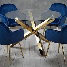 a glass table with blue chairs around it and a gold metal frame on the base