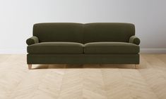 a green couch sitting on top of a wooden floor next to a white painted wall