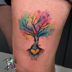 a colorful tree tattoo on the side of a woman's thigh with hearts and leaves