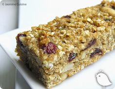 a white plate topped with granola bars on top of a wooden table next to a bird