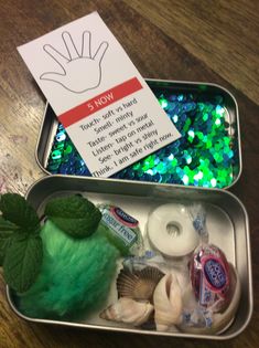 two tins filled with assorted items on top of a wooden table next to a sign