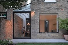 a person sitting at a table in front of a brick building with an open door