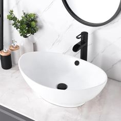 a white sink sitting under a mirror next to a black faucet