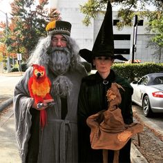 two people dressed up as wizard and witch with a bird on their arm, standing next to each other