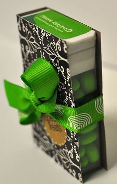 an open box with a green ribbon tied around the front and side of it, sitting on a white surface