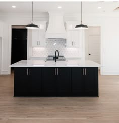 a large kitchen with white cabinets and black appliances