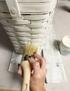 a person is using a brush to paint a basket