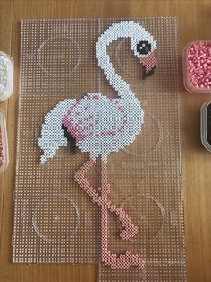 a cross stitch flamingo is sitting on the floor next to a pair of scissors