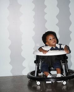 a small child sitting in a high chair with wheels on the floor and smiling at the camera