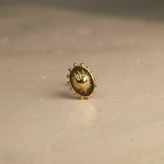 a gold ring with a sun design on the front and center, sitting on a white surface