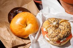 a bagel sandwich sitting next to a donut on top of a paper wrapper