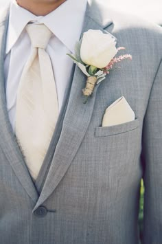 a man in a gray suit with a white rose boutonniere on his lapel