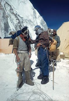 several people standing in the snow near a mountain