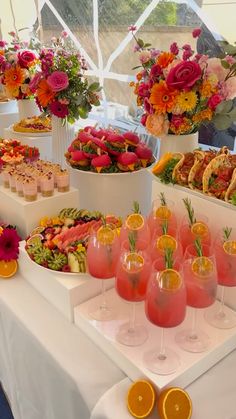 there are many different types of food on the table with wine glasses and oranges