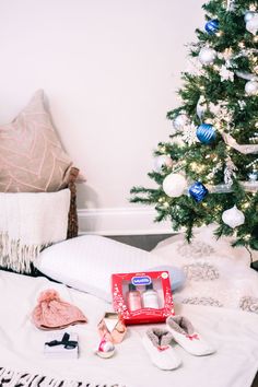 a small christmas tree sitting on top of a bed next to pillows and slippers