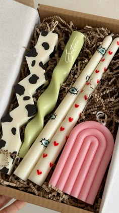 three candles in a gift box with cow print and hearts on them, one is shaped like an oar