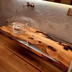 a glass bowl sitting on top of a wooden counter next to a faucet