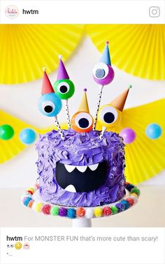 a birthday cake with purple frosting and eyes on top, surrounded by party decorations