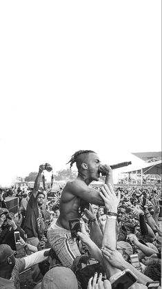 a black and white photo of a man holding a microphone in front of a crowd