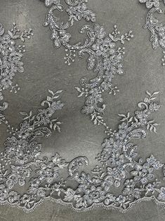 an embroidered fabric with silver flowers and leaves on the bottom, along with white thread