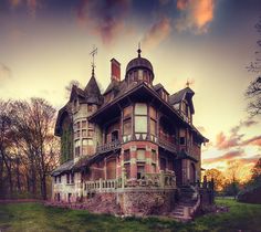 an old, run down house sits in the middle of a grassy field at sunset