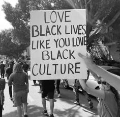 a group of people walking down the street holding signs that read love black lives like you love black culture