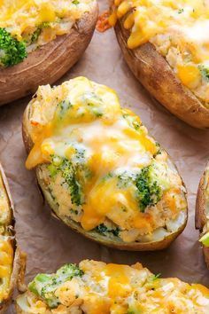 baked potatoes with broccoli and cheese on them sitting on a piece of parchment paper