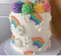 a person is decorating a cake with rainbow icing