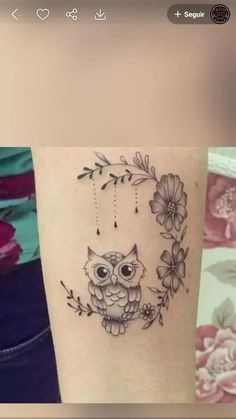 an owl tattoo on the arm with flowers and beads hanging from it's back