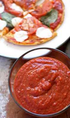 two small pizzas with sauce and cheese on them sitting on a table next to each other