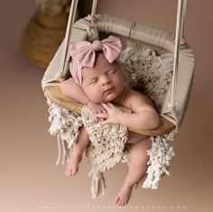 a baby is sleeping in a hammock with a pink bow