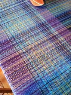 a close up of a table with a blue and purple plaid pattern on it, next to a wooden spoon