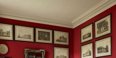 a living room with red walls and pictures on the wall