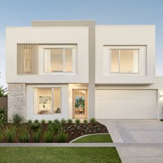 a white two story house with lots of windows and plants in the front yard at dusk