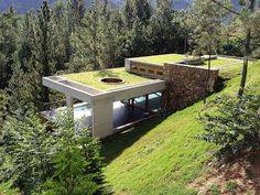 an aerial view of a house with grass on the roof and trees in the background