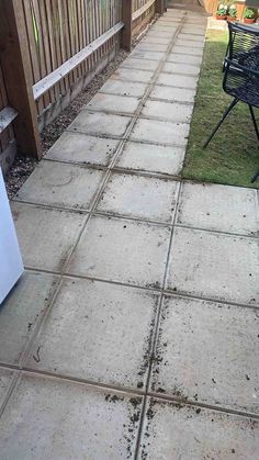 a cement patio with grass and dirt on the ground